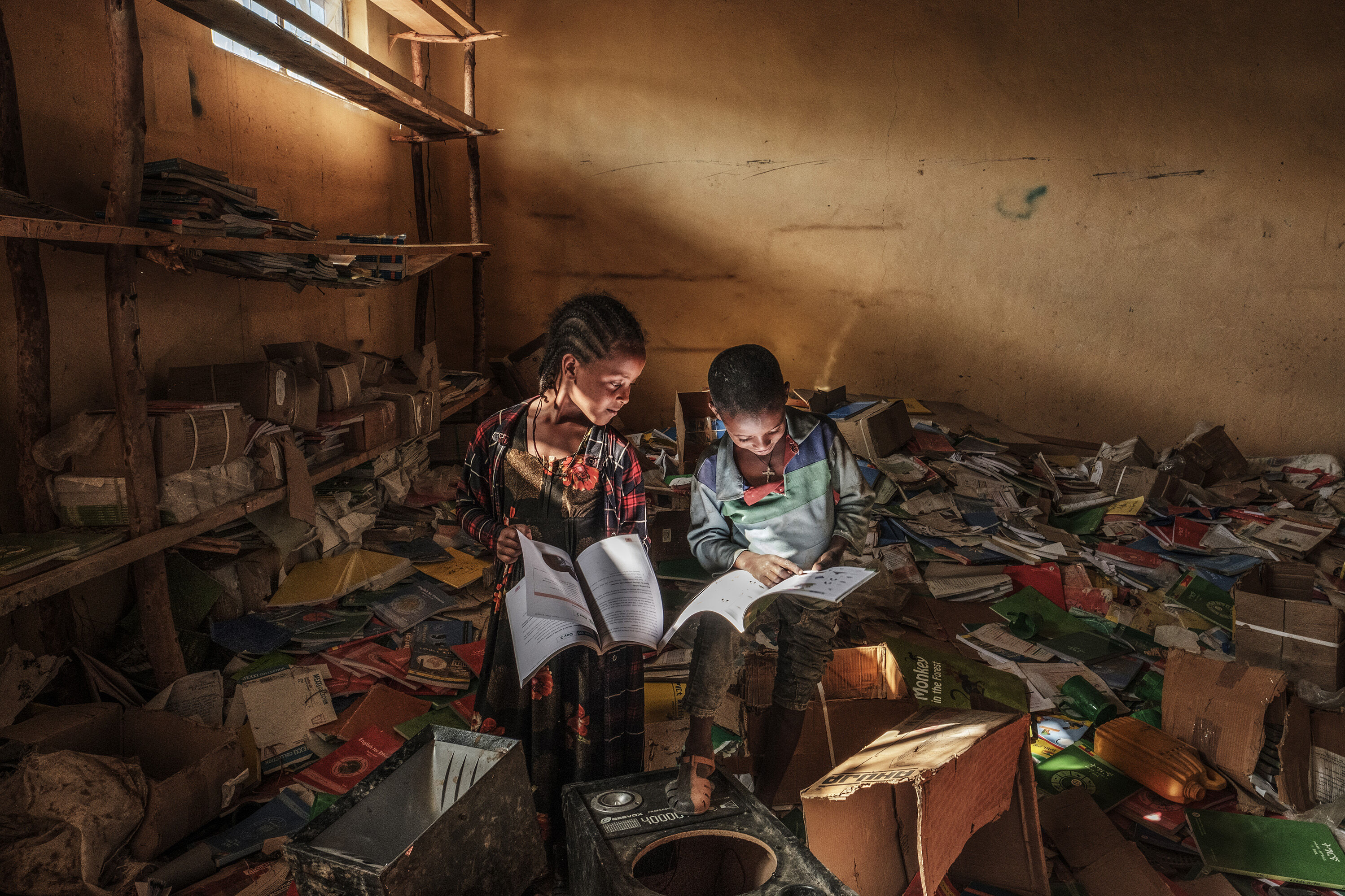 Children look at books in the library of an elementary school that was damaged during the fightings that broke out in Ethiopia's Tigray region, in the village of Bisober, on December 9, 2020. The November 14 killings represent just one incident of civilian suffering in Bisober, a farming village home to roughly 2,000 people in southern Tigray. In retrospect, Bisober residents say, the first sign of the conflict came seven months ago, when members of the Tigray Special Forces took over the village elementary school, which had been emptied because of the coronavirus pandemic.